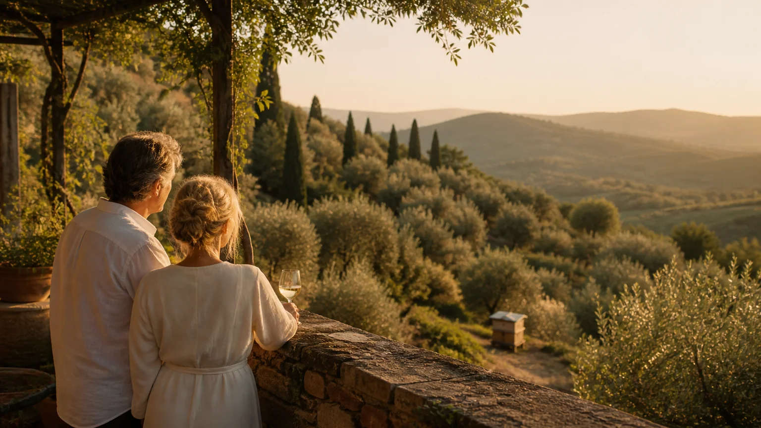 A couple sharing a quiet golden-hour view across Tuscan hills with a beehive in the landscape